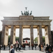 Germany – Berlin Brandenburg Gate with tourists gathered in the foreground on a sunny day.