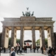 Brandenburg Gate with tourists gathered in the foreground on a sunny day.
