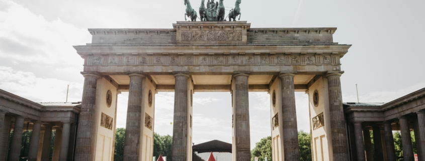 Brandenburg Gate with tourists gathered in the foreground on a sunny day.
