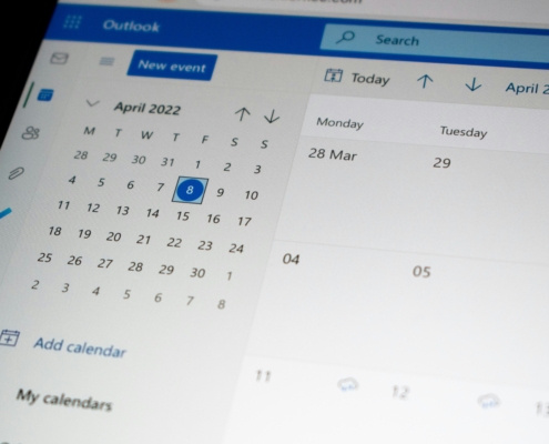 Outlook calendar showing April 2022 in month view with a highlighted date and left navigation icons, plus a blue event button at top left.
