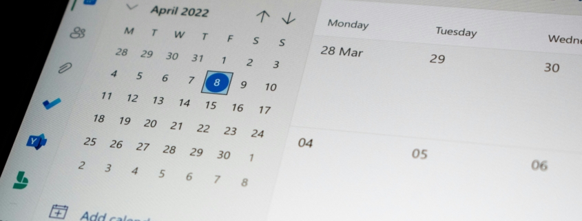 Outlook calendar showing April 2022 in month view with a highlighted date and left navigation icons, plus a blue event button at top left.